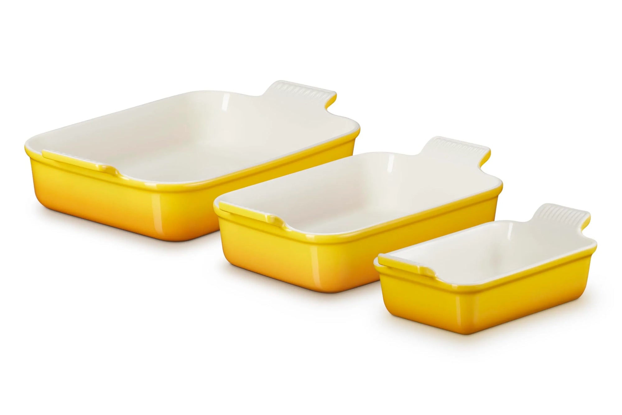 Three rectangular yellow and white glass baking dishes in different sizes, arranged diagonally on a white background.
