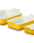 Three rectangular yellow and white glass baking dishes in different sizes, arranged diagonally on a white background.