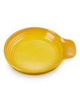 A bright yellow ceramic spoon rest with a small handle on the right side, shown on a plain white background.