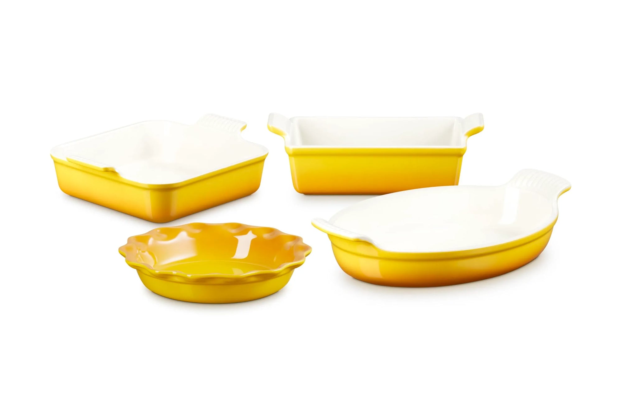 Four yellow and white ceramic baking dishes of different shapes and sizes arranged on a plain white background.