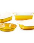 Four yellow and white ceramic baking dishes of different shapes and sizes arranged on a plain white background.