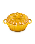 A glossy yellow-orange ceramic lidded casserole dish shaped like a pumpkin, featuring two side handles and a ribbed surface, set against a plain white background.