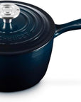 A Le Creuset dark blue enameled cast iron saucepan with a matching lid and a silver knob, shown on a white background.