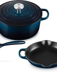 Three-piece Le Creuset cookware set in deep teal enamel, including a round lidded pot, a smaller lidded pot, and a skillet, shown on a white background.