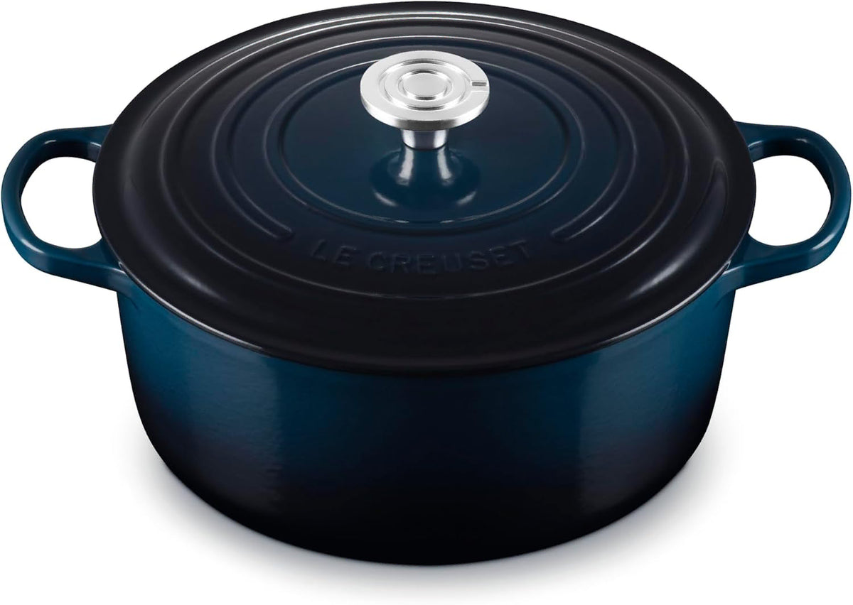 A dark blue enameled cast iron Dutch oven with a matching lid and side handles, featuring a silver metal knob, shown on a white background.
