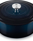 A dark blue enameled cast iron Dutch oven with a matching lid and side handles, featuring a silver metal knob, shown on a white background.