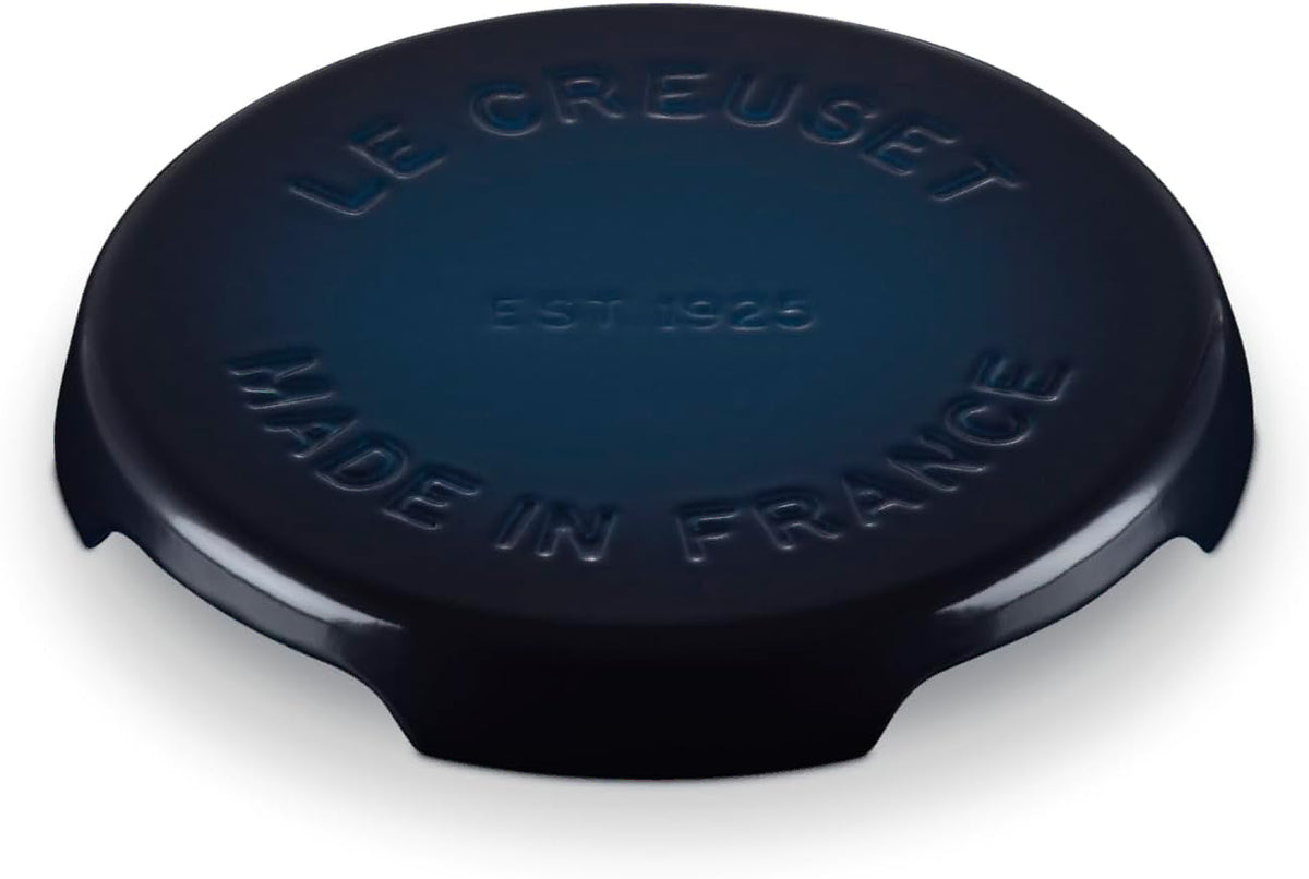 A dark blue Le Creuset round trivet with embossed text reading 'LE CREUSET', 'EST 1925', and 'MADE IN FRANCE', shown on a white background.