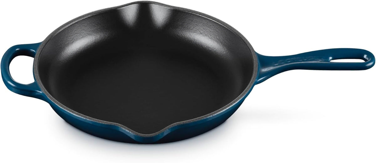 A cast iron skillet with a dark blue enameled exterior and a black non-stick interior, shown on a white background.