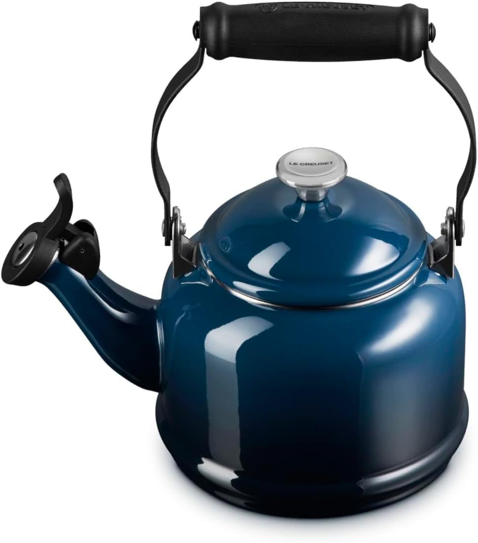 A dark blue enamel stovetop kettle with a black handle and spout, featuring a silver metal lid knob with the Le Creuset brand name.