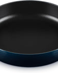A round cast iron skillet with a dark blue exterior and a black non-stick interior, featuring two loop handles on a white background.