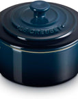 A dark blue Le Creuset enameled cast iron pot with a matching lid, featuring side handles and a gold accent line, shown on a white background.