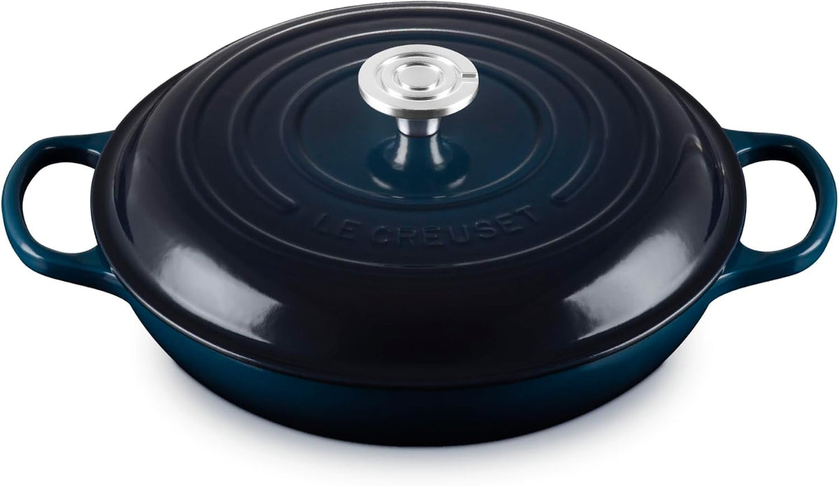 Le Creuset enameled cast iron oval lidded casserole dish in dark teal with a silver-tone knob, shown on a white background.