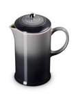 A ceramic French press coffee maker with a black and gray gradient design, featuring a matching black lid with a silver metal knob and a white Le Creuset logo embossed on the lid.