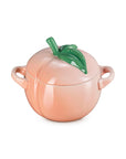 Peach-shaped ceramic container with a green leaf on a white background