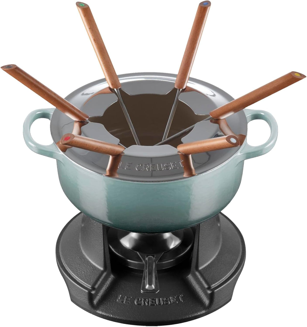 Le Creuset fondue set with a light blue enameled pot, black cast-iron base, and copper-colored cheese forks and utensils, shown on a white background.
