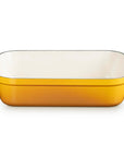 A rectangular yellow enameled baking dish with two side handles and a white interior, shown on a clean white background.