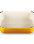 A rectangular yellow enameled baking dish with a cream-colored interior and two yellow side handles, shown on a plain white background.