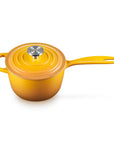 A small yellow enameled cast iron saucepan with a matching lid and a silver knob, set against a plain white background.