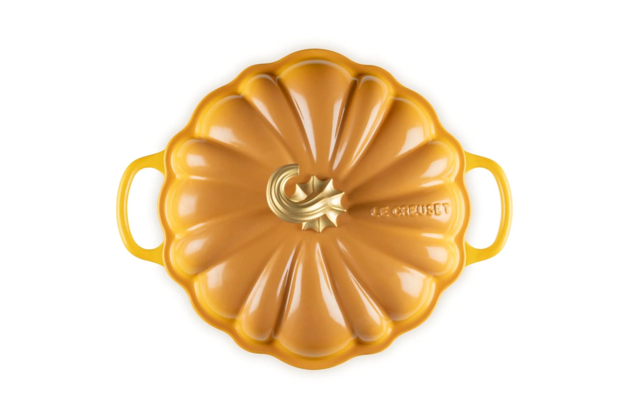 A Le Creuset pumpkin-shaped enameled cast iron Dutch oven lid, featuring a golden yellow-orange finish with a central gold logo and side handles, shown on a solid white background.