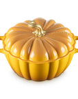 A pumpkin-shaped enameled cast iron casserole dish with a lid, featuring a glossy orange-yellow finish and a small gold-toned faux stem on a white background.