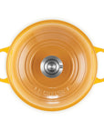 Top-down view of a Le Creuset enameled cast iron pot in a vibrant orange-yellow color, featuring two side handles and a stainless steel knob on the lid, set against a plain white background.