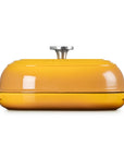 A round yellow enameled cast iron casserole dish with a matching lid and side handles, featuring a silver metal knob on top, set against a plain white background.