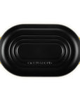 A black oval cast iron skillet with bright yellow handles, shown from a top-down view on a solid white background.
