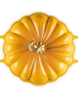 A yellow enameled cast iron Dutch oven with a pumpkin-shaped lid and side handles, photographed from a top-down perspective on a white background.
