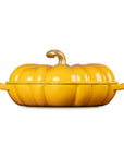 A bright yellow pumpkin-shaped lidded casserole dish with side handles and a small stem on top, photographed against a plain white background.