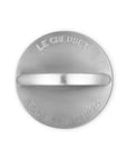 Top view of a circular silver-toned metal grill press with a horizontal center bar and engraved text reading 'LE CREUSET' and 'EST FRANCE 1925' on a plain white background.