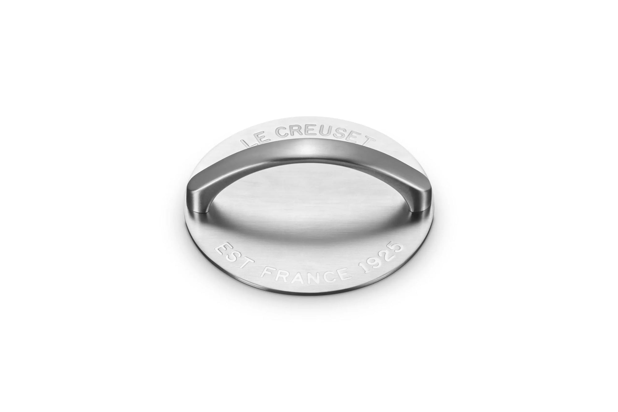A round stainless steel grill press with a curved handle, featuring engraved text reading 'LE CREUSET' and 'EST. FRANCE 1925' on a white background.