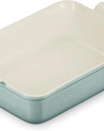 A rectangular ceramic baking dish with a light green exterior and a cream-colored interior, featuring integrated side handles.