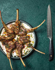 Grilled lamb chops on a plate with a knife on a green background