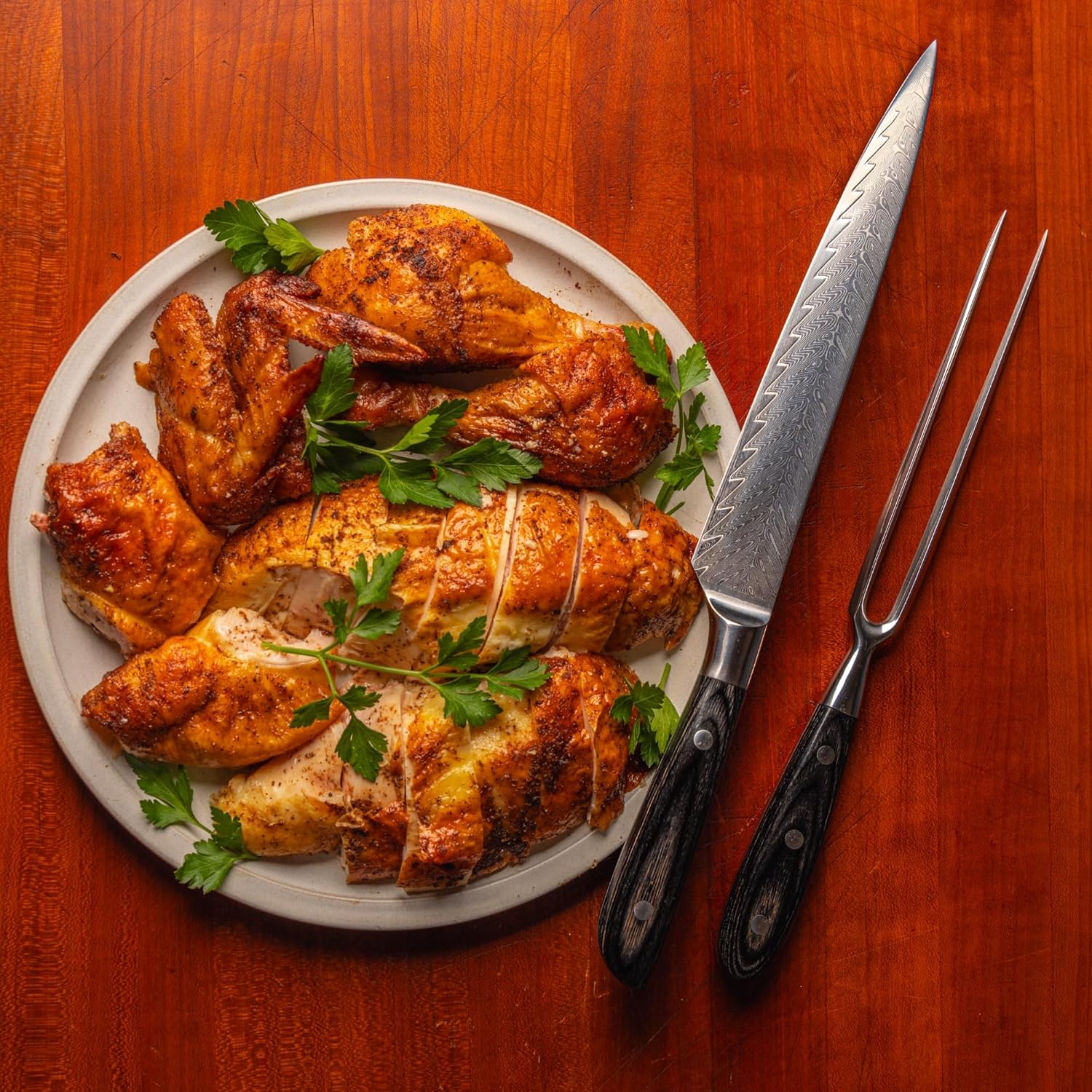 Plated chicken with a knife and fork on a wooden surface