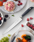 Fruits, pastries, bread knife, and paring knife on a marble surface