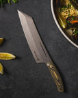 Chef's knife on a dark surface with lemons and a dish of pasta with mussels.