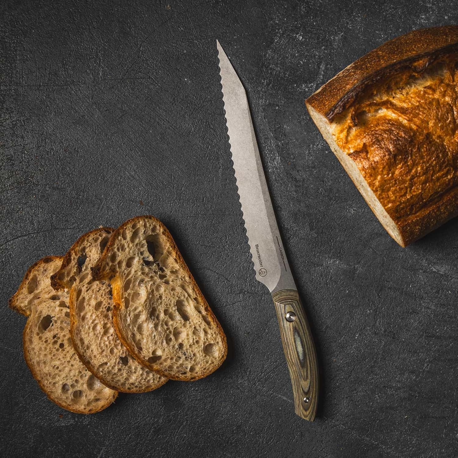 Sliced bread with a bread knife on a dark surface
