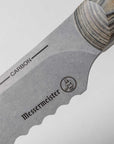 Close-up of a Messermeister knife blade with 'Carbon' and brand logo on a light gray background