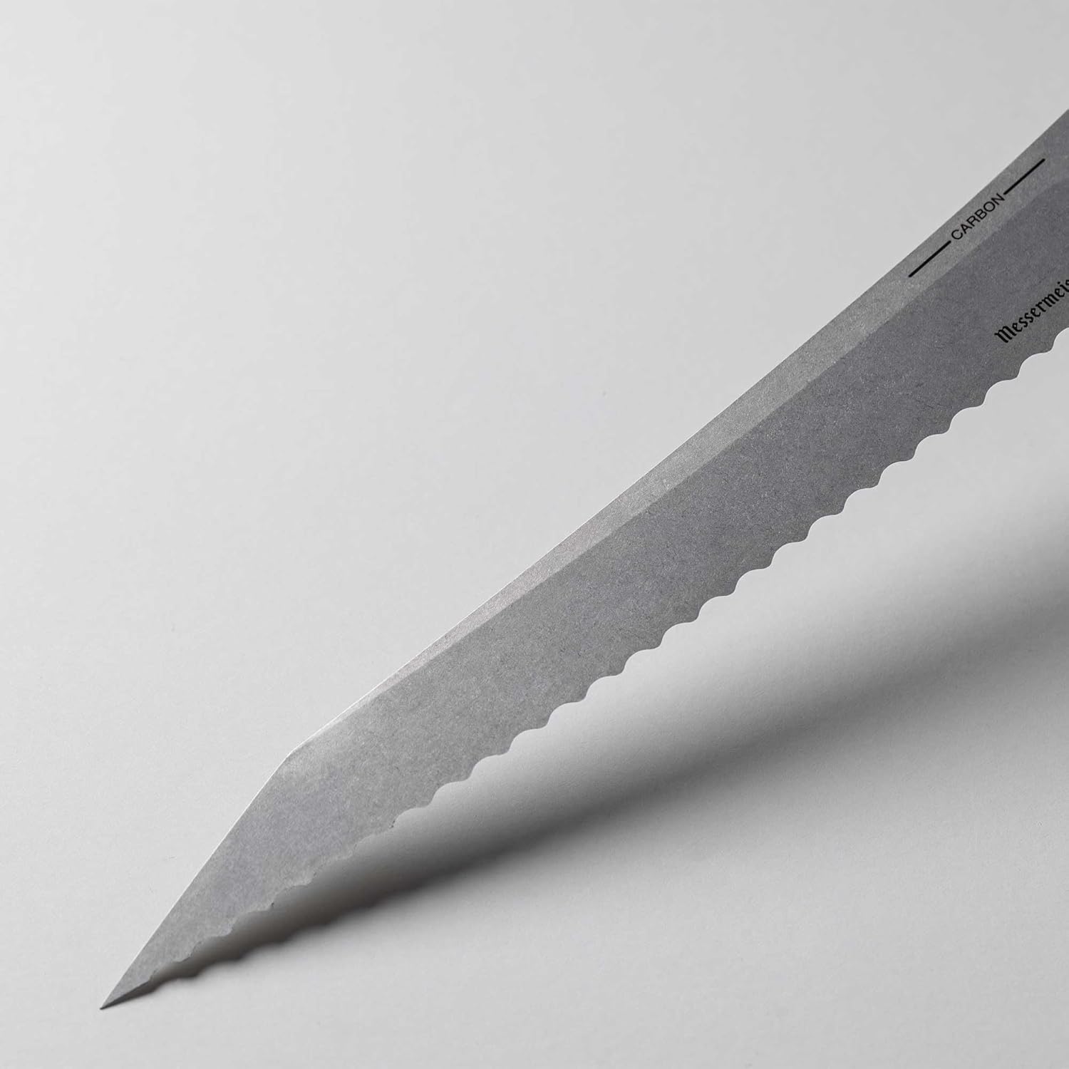 Knife blade with scalloped edge on a light gray background