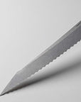 Knife blade with scalloped edge on a light gray background
