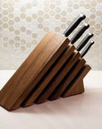 Set of knives in a wooden block on a kitchen counter with a tiled backsplash.
