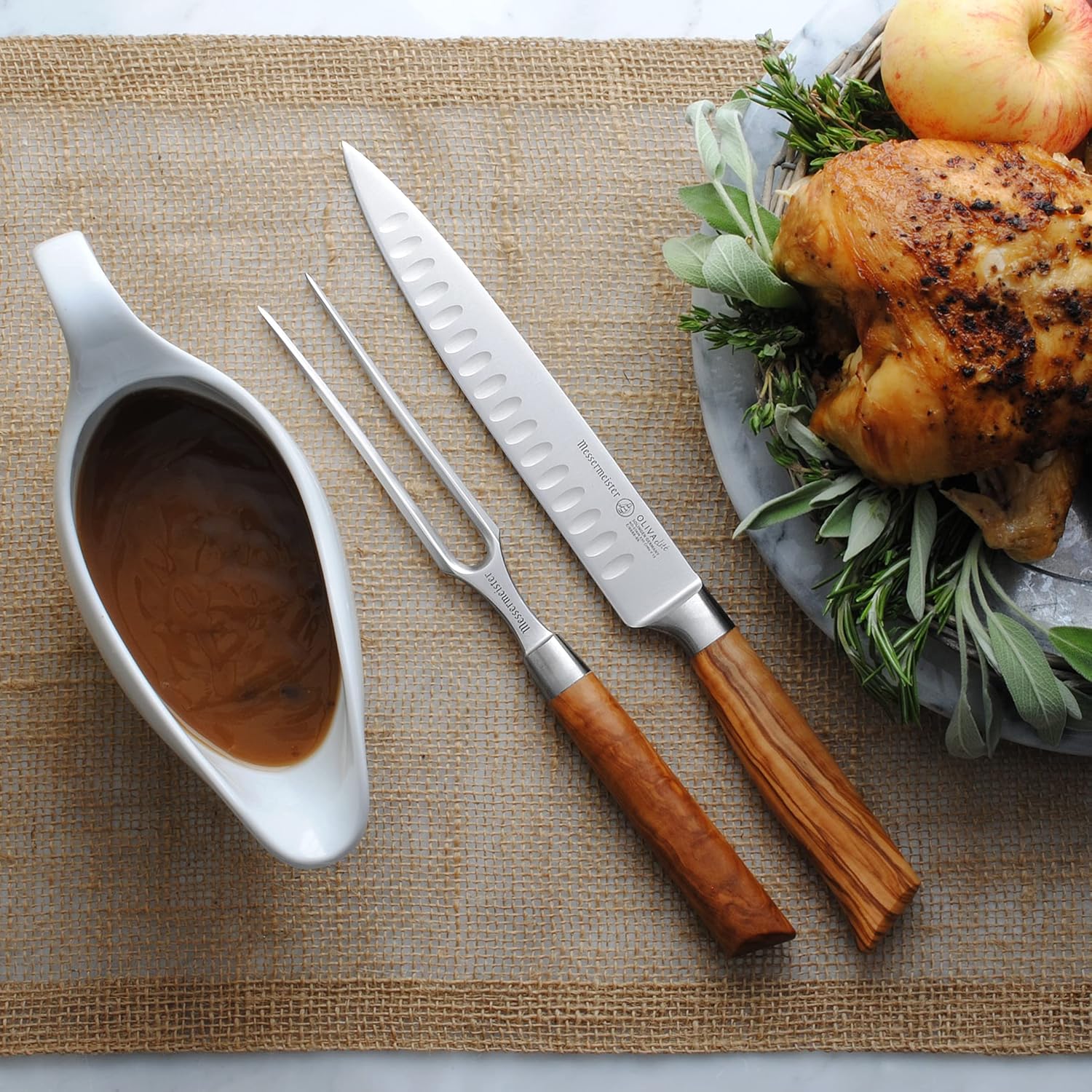 Roasted chicken with carving utensils and a gravy boat on a woven mat