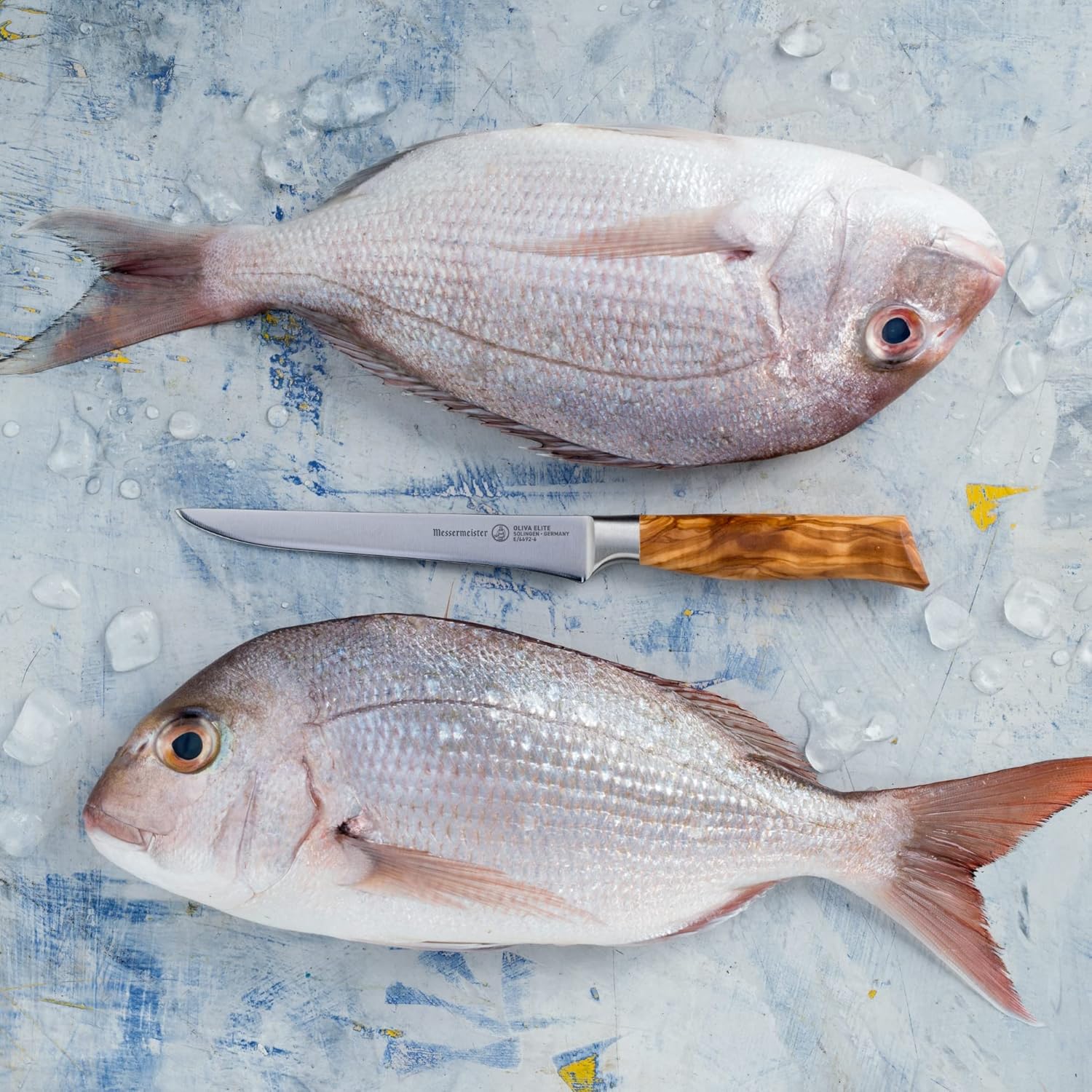 Two raw fish on a textured surface with a knife.