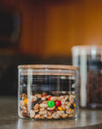 Small glass airscape filled with trail mix in a kitchen setting with a airtight lid and a bamboo lid