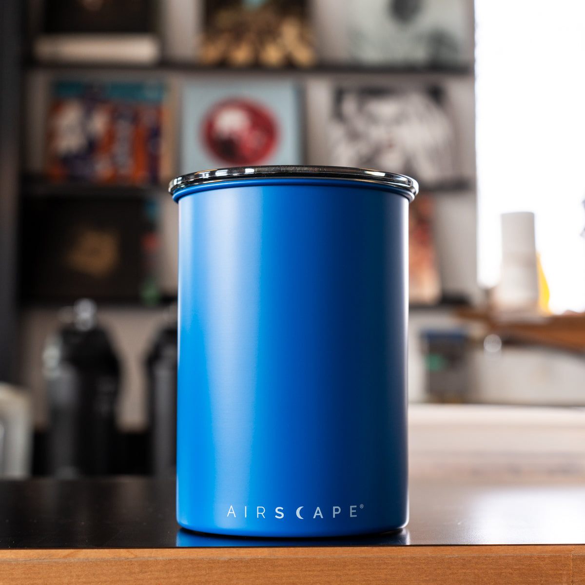 Matte blue tumbler with 'AIRSCAPE' branding on a wooden surface with a blurred background