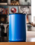 Matte blue tumbler with 'AIRSCAPE' branding on a wooden surface with a blurred background