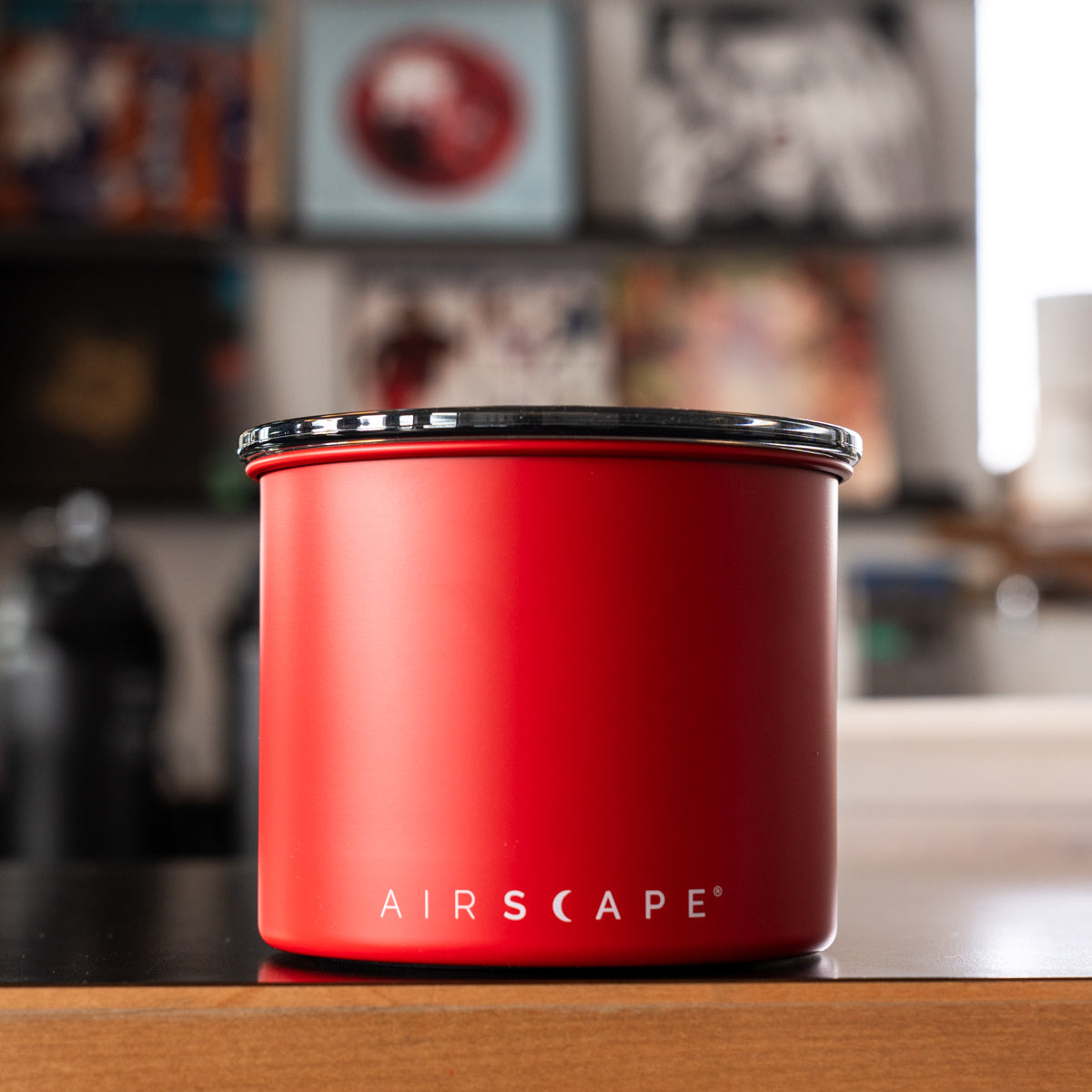 Red canister with black lid on a wooden surface, blurred background