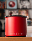 Red canister with black lid on a wooden surface, blurred background