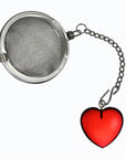 A stainless steel ball tea infuser with a short chain and a red heart-shaped charm, shown on a plain white background.