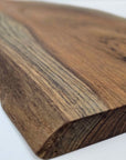 Close-up of a wooden cutting board showing the natural edge with a white background